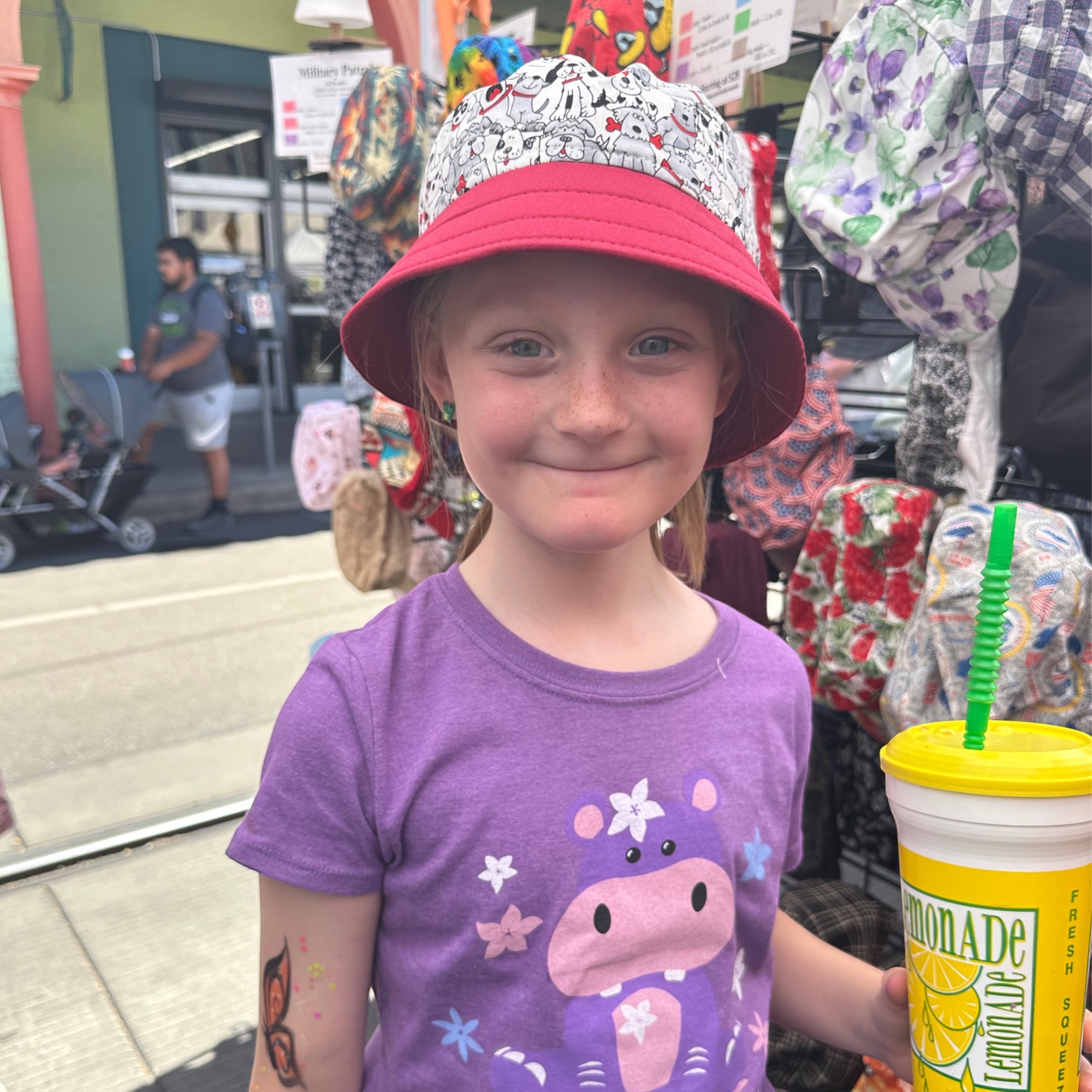 Child Wearing Dog Print Bucket Hat at Street Fair Young girl wearing dog print bucket hat holding lemonade at Tucson street fair