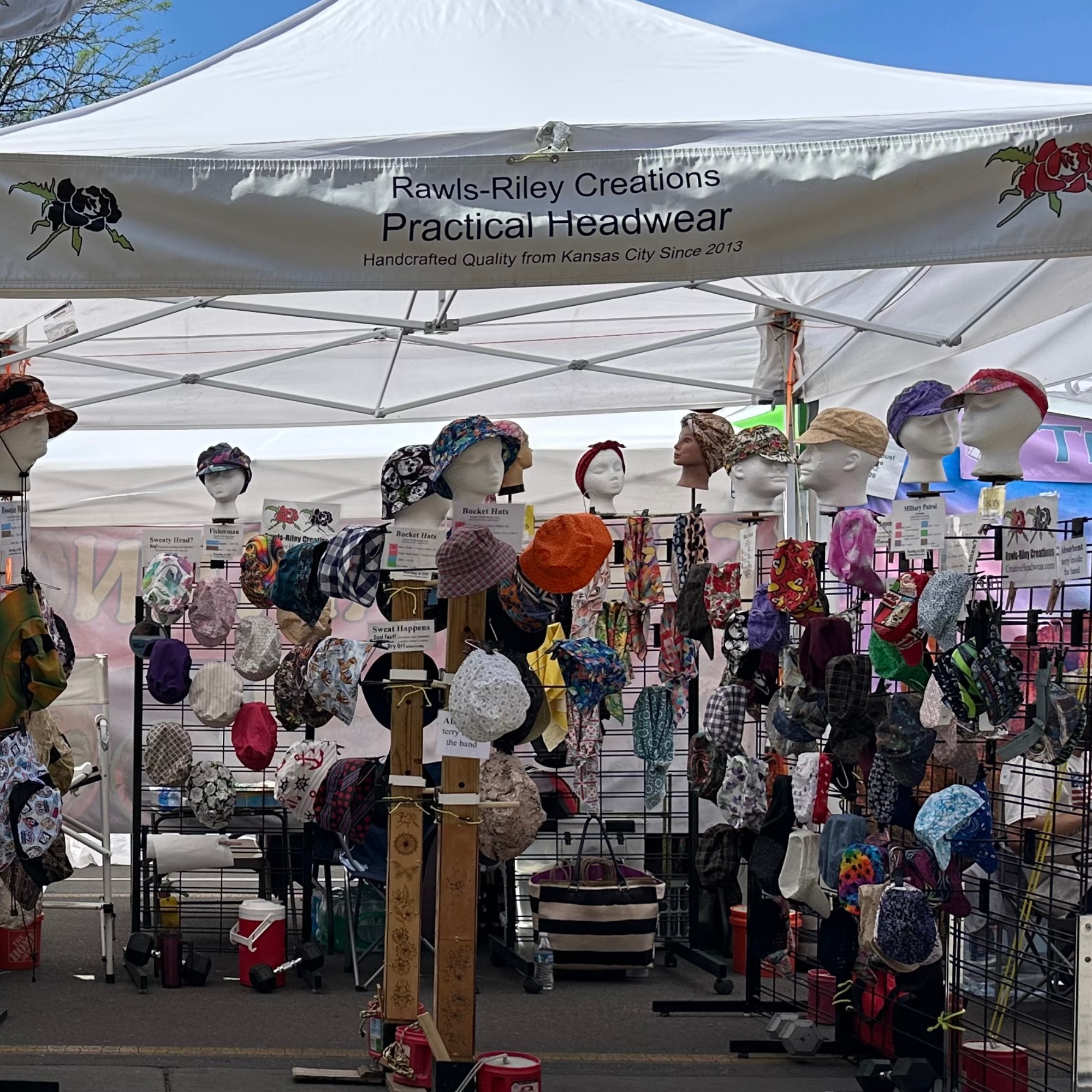Rawls-Riley Creations Event Booth – Hats and Caps Display Rawls-Riley Creations booth display featuring handcrafted hats, caps, and headwear at an outdoor event